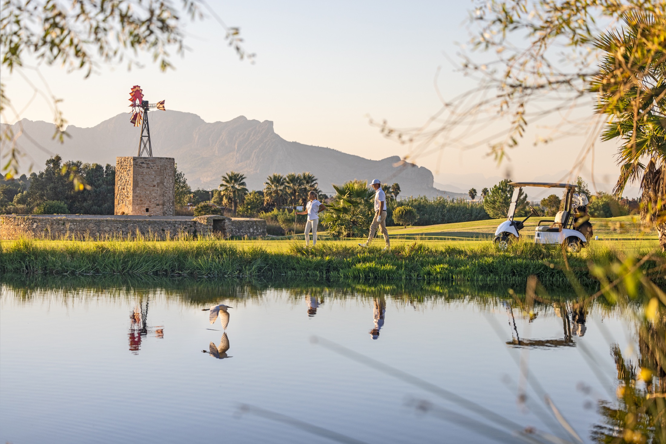 Golfers beside the lake at La Sella Golf with Montgó beyond